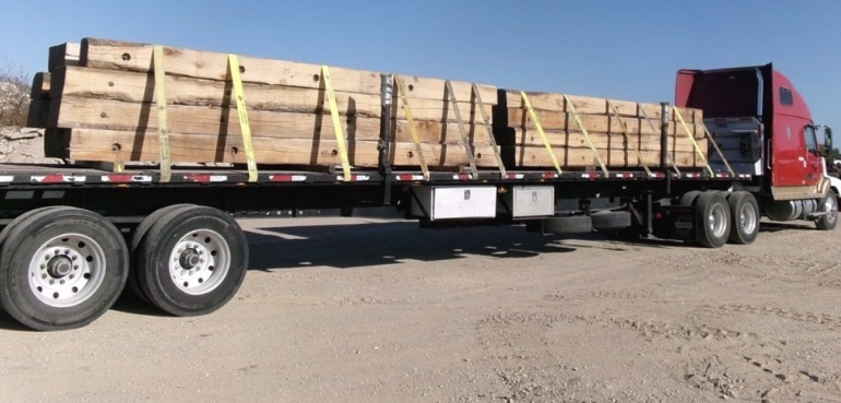 Flatbed trailer carrying secured heavy timber crane mats
